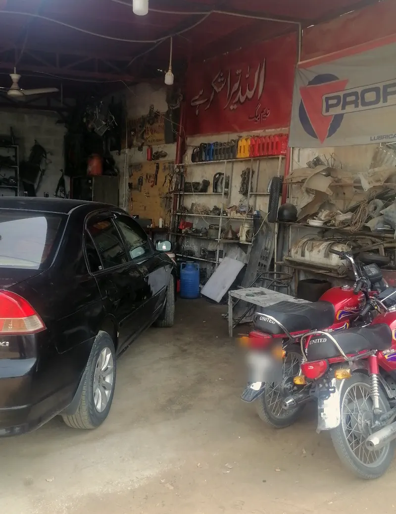 Inside the covered bay, with a car, motorbikes and shelves of parts and oil